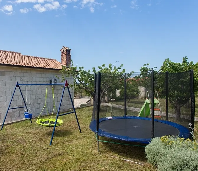Private outdoor children's playground with swing, slide, and trampoline
